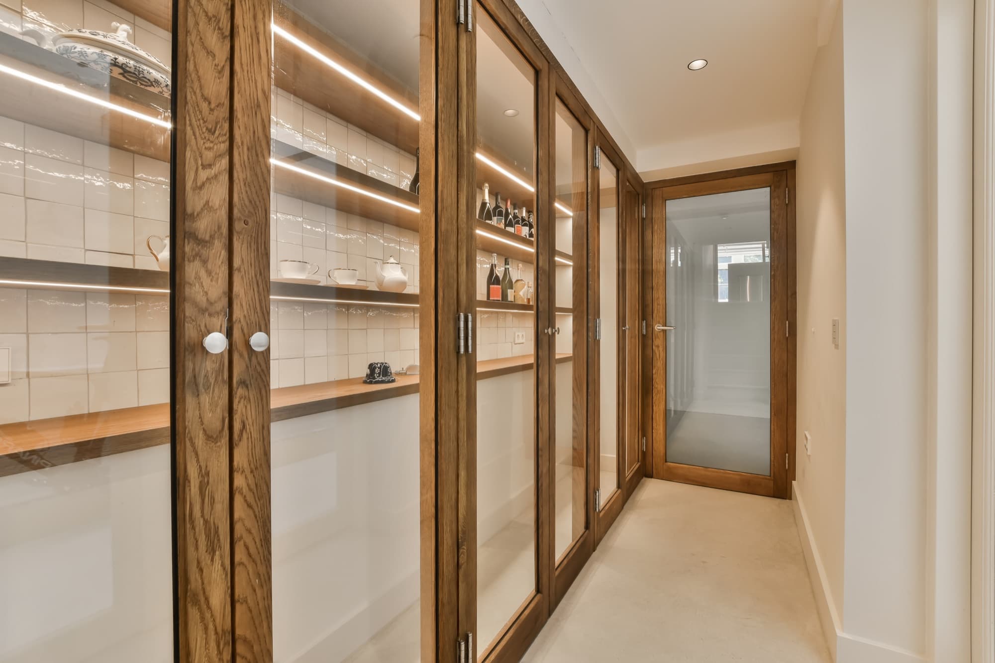Bespoke oak joinery with glazed cabinet doors, integrated lit shelving and a matching oak-framed door