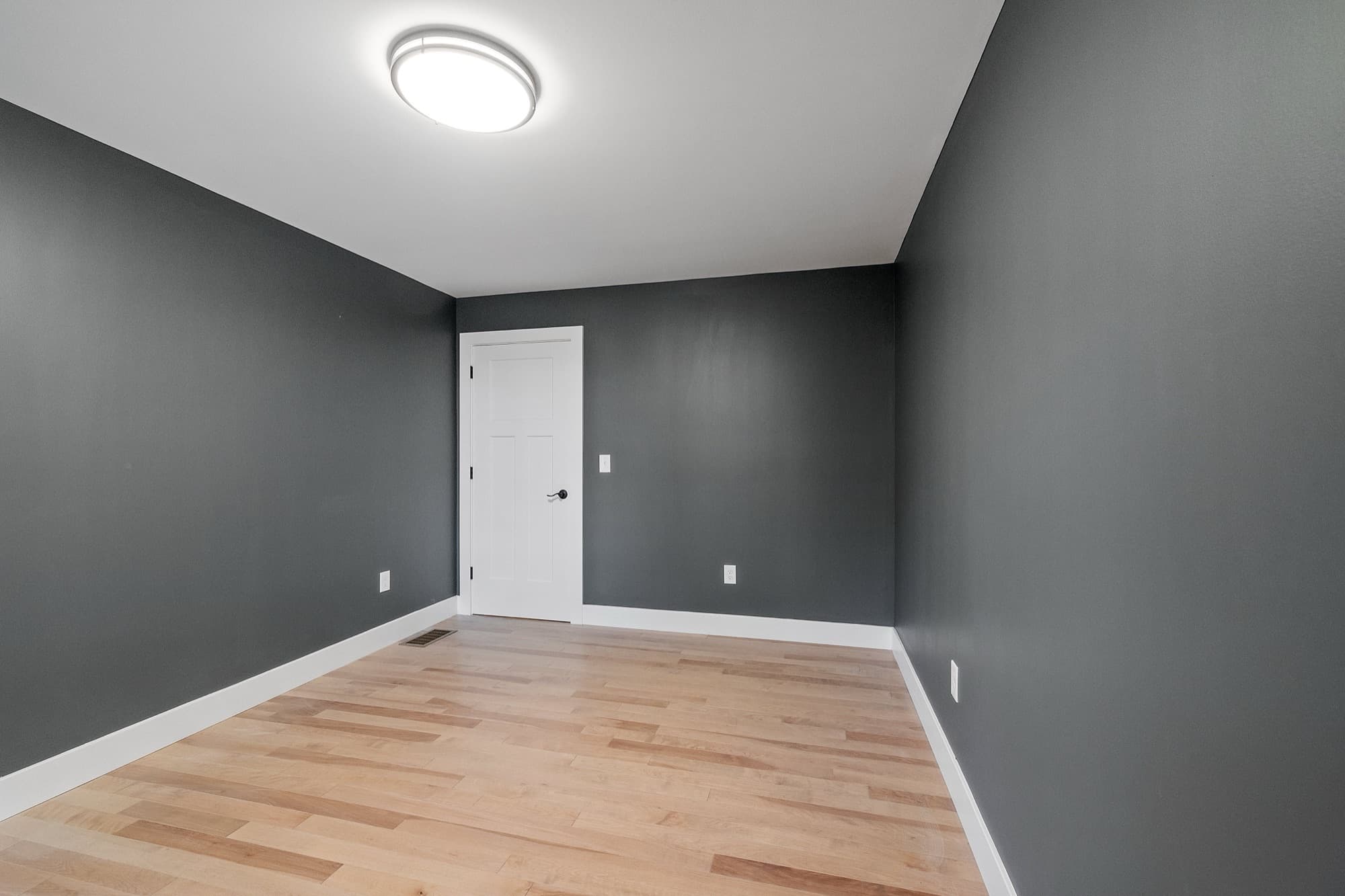 Freshly decorated room with charcoal walls cut in cleanly against a white ceiling and skirting